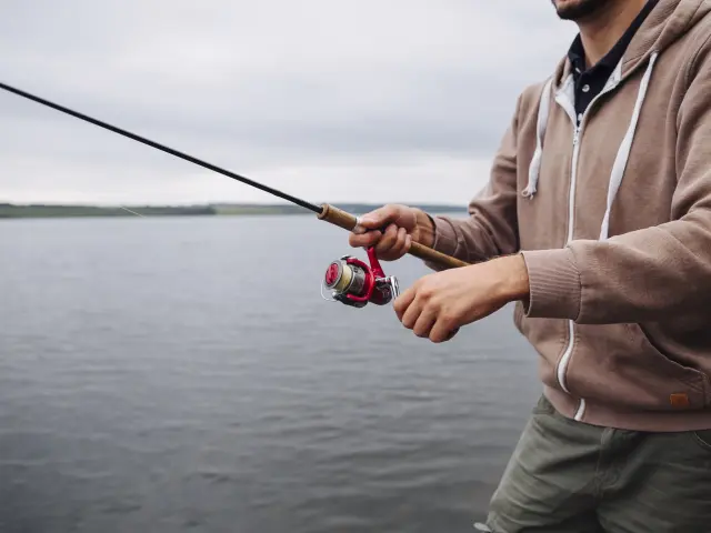 close-up-man-s-hand-holding-fishing-rod-near-lake.jpg